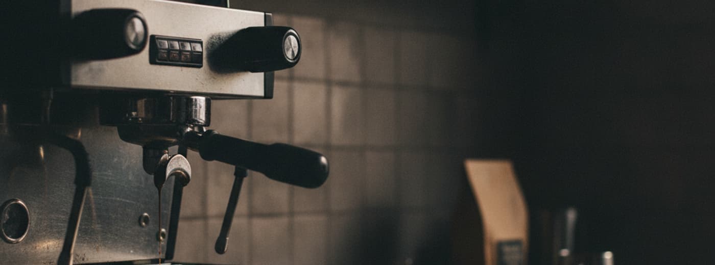 Prosumer espresso machine on a wooden bench, side-lit against a dark backdrop